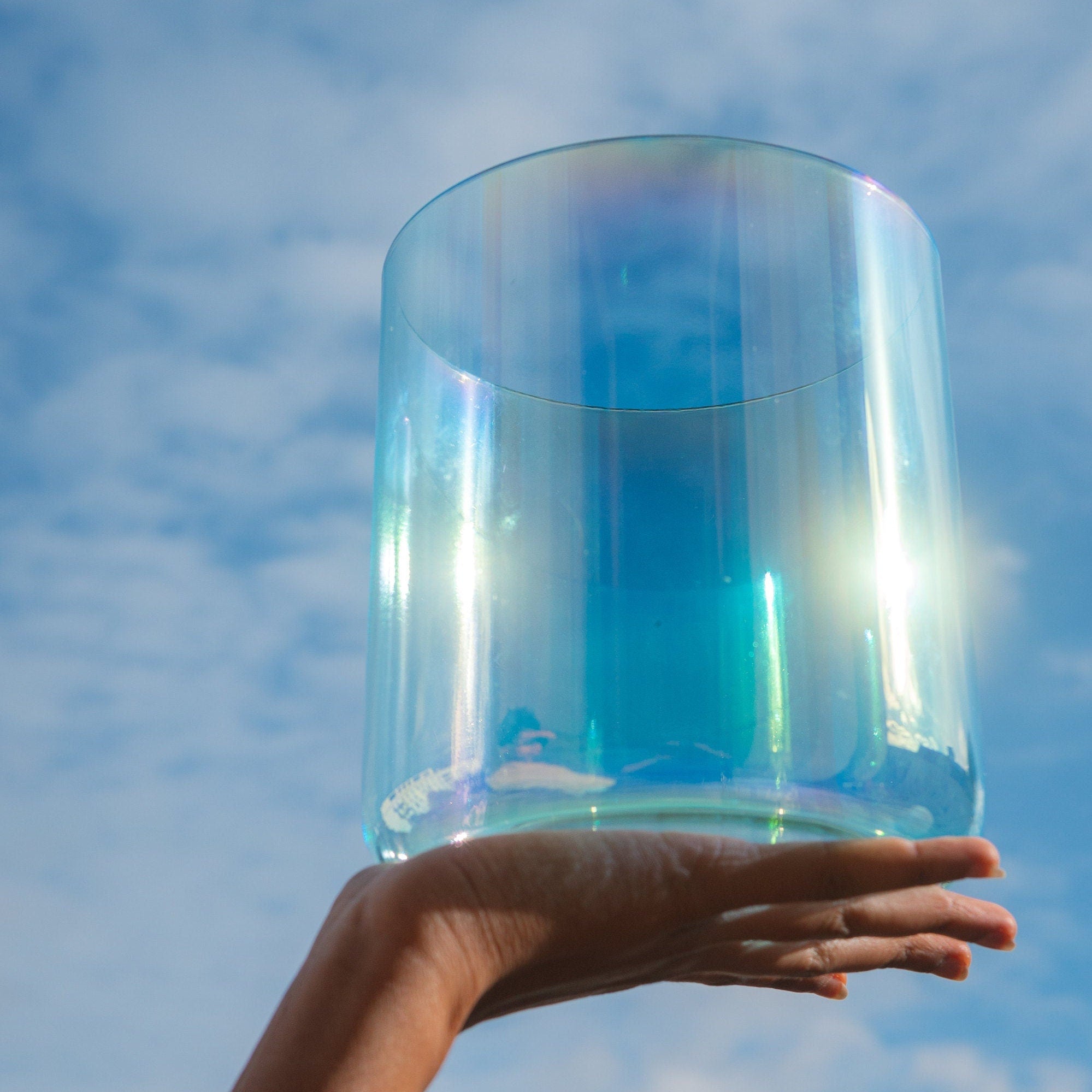Holding Cosmic Sound Bowls® 'Ocean' Singing Bowls in the air with sky