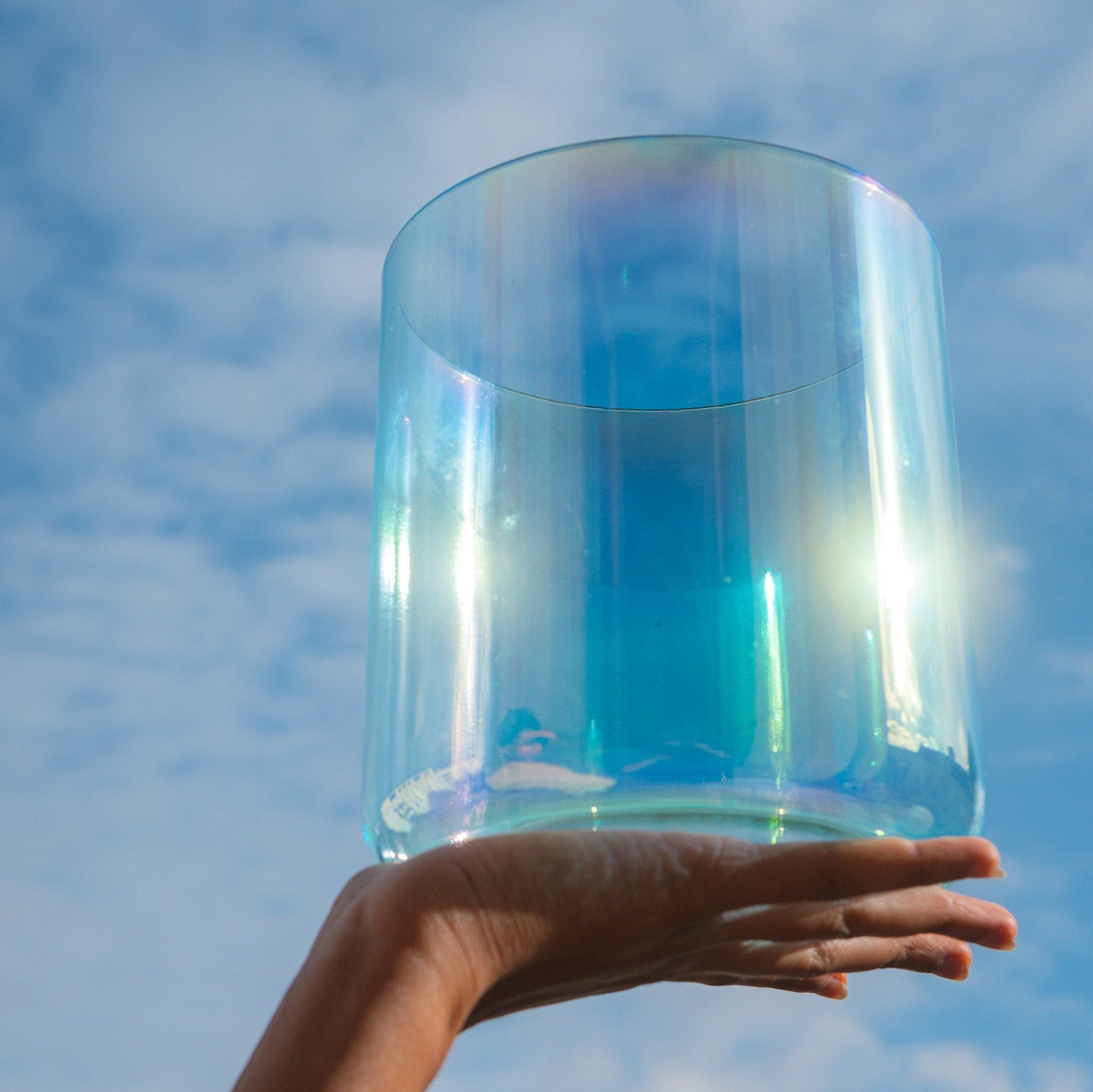 Holding Cosmic Sound Bowls® 'Ocean' Singing Bowls in the air with sky